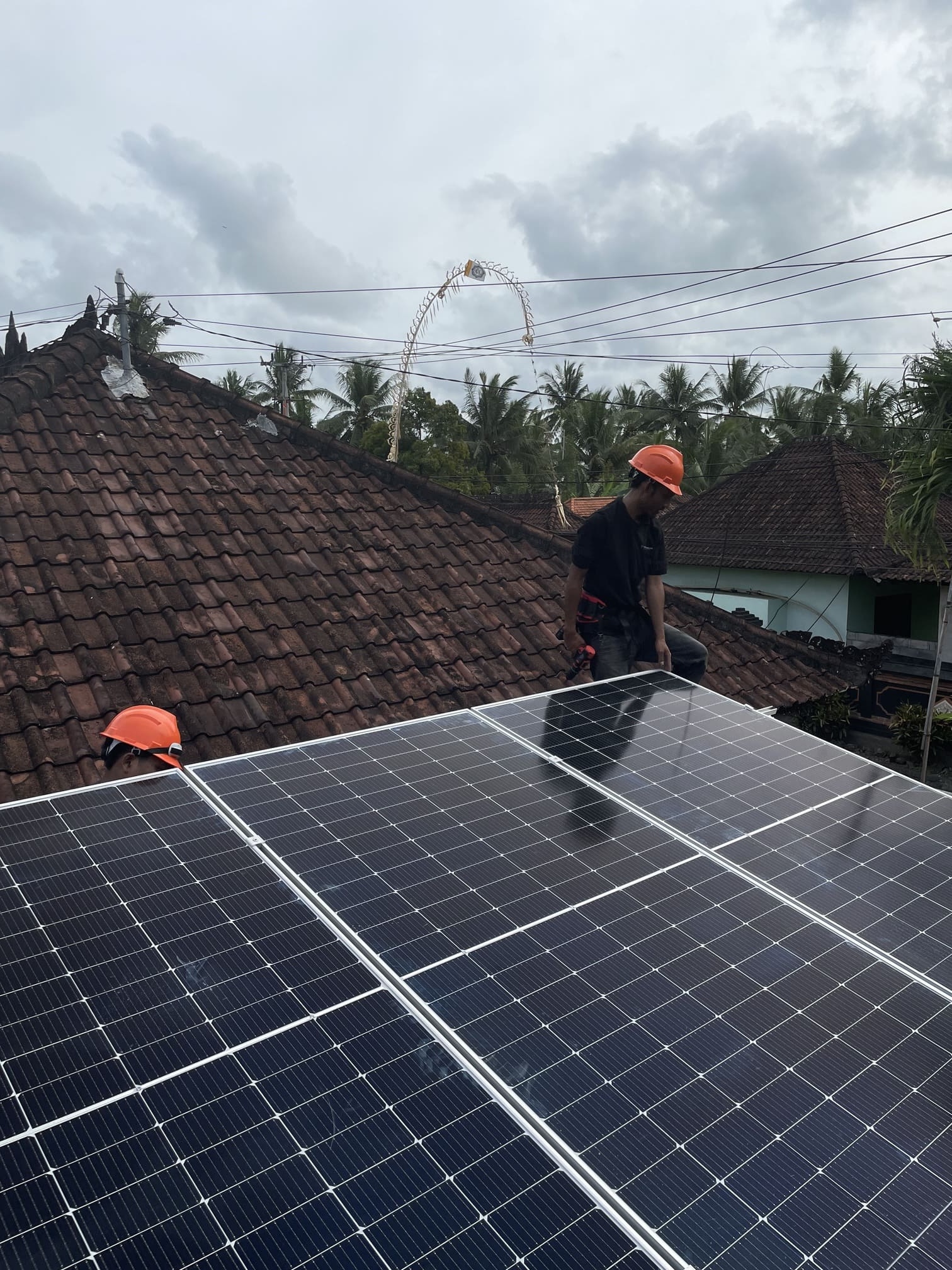 Technician on a traditional Balinese roof installing solar panels