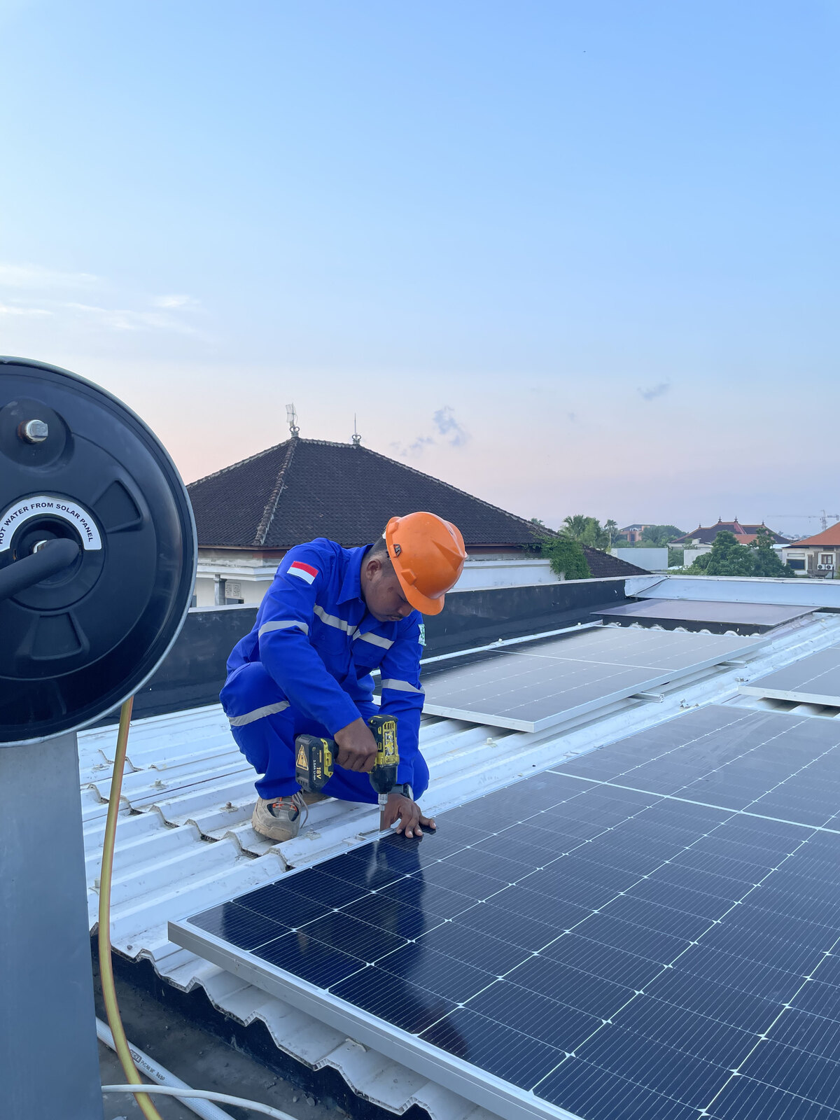 Technician on a traditional Balinese roof installing solar panels
